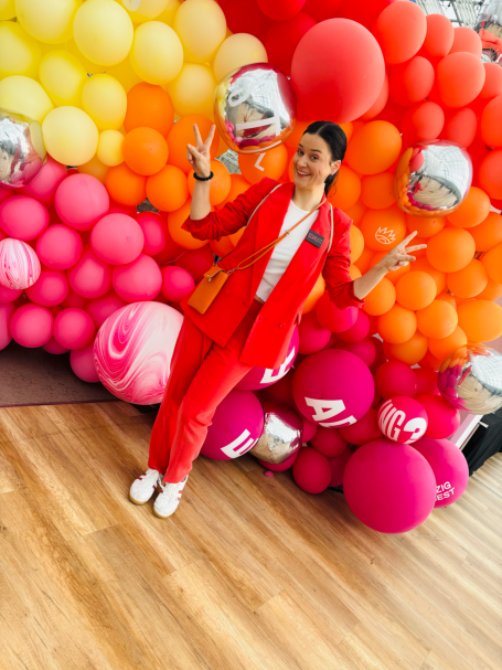 Frau im Hosenanzug vor bunten Luftballons