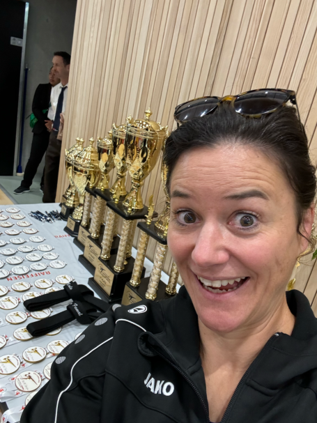 Frau sehr fröhlich vor Medaillen und Pokalen